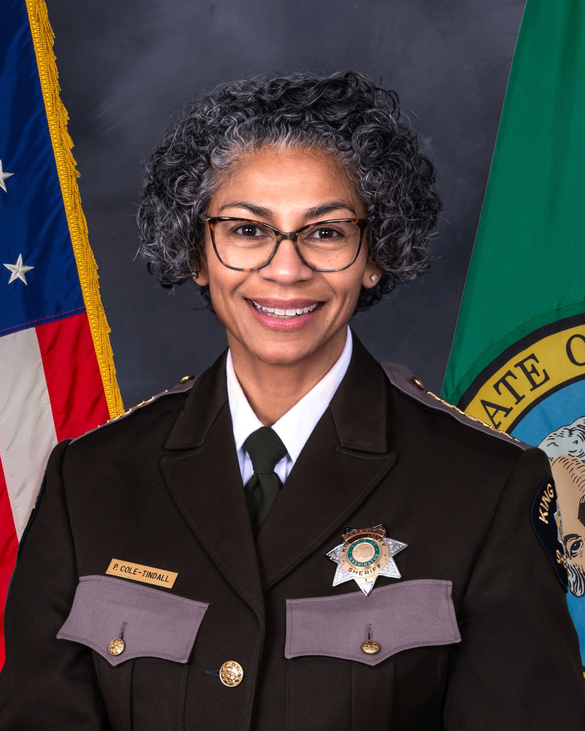 Official photo of Patti Cole-Tindall in her dress uniform. She is a middle-aged black female with a tight curled pixie cut, with a bright open smile.