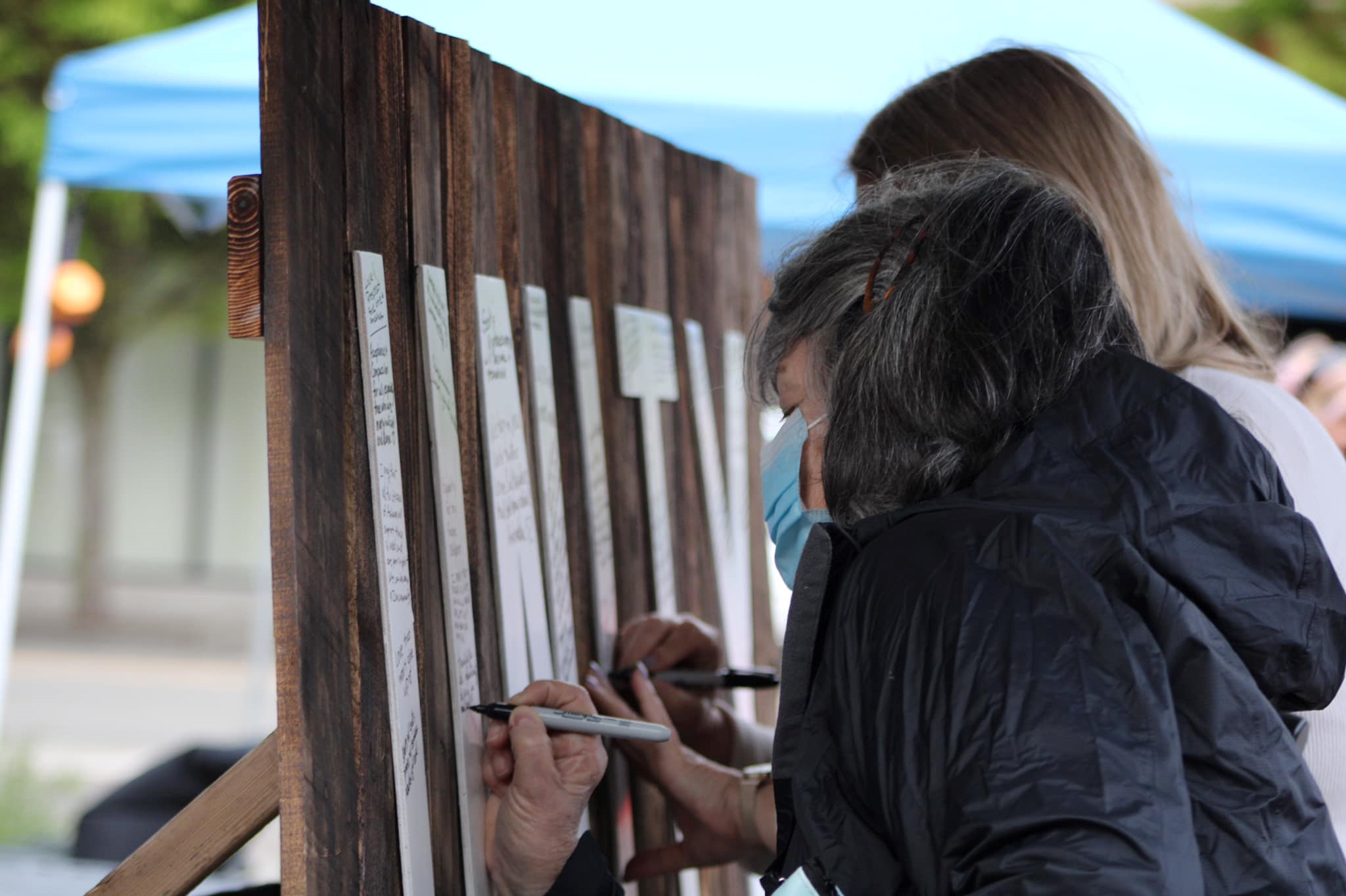two attendees write messages on a large sign that reads UNITY during City of Auburn National Day of Prayer Event, 2021
