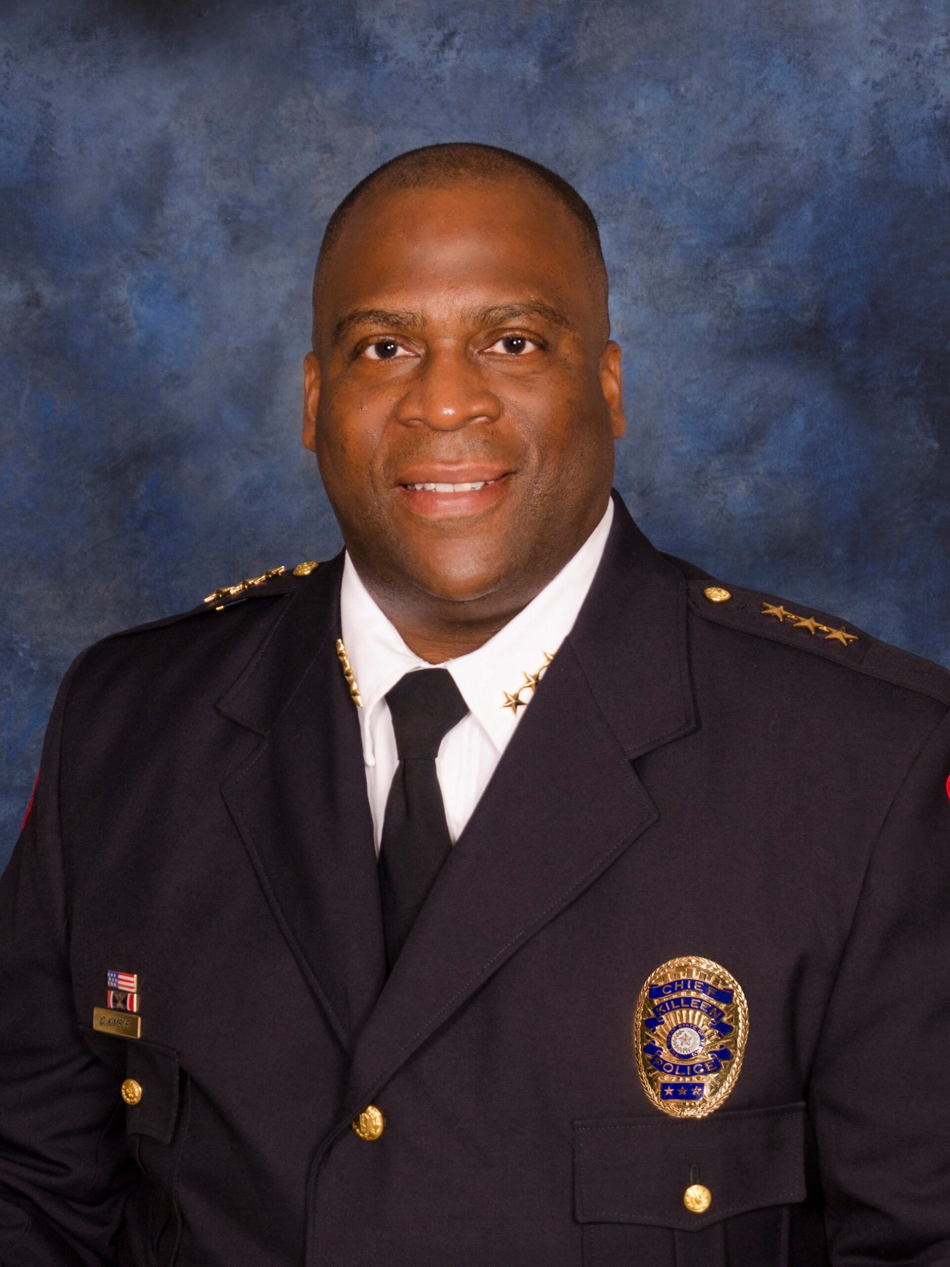 Official photo of Chief Charles Kimble in his dress uniform. He is a pleasant looking middle-aged black male, smiling.