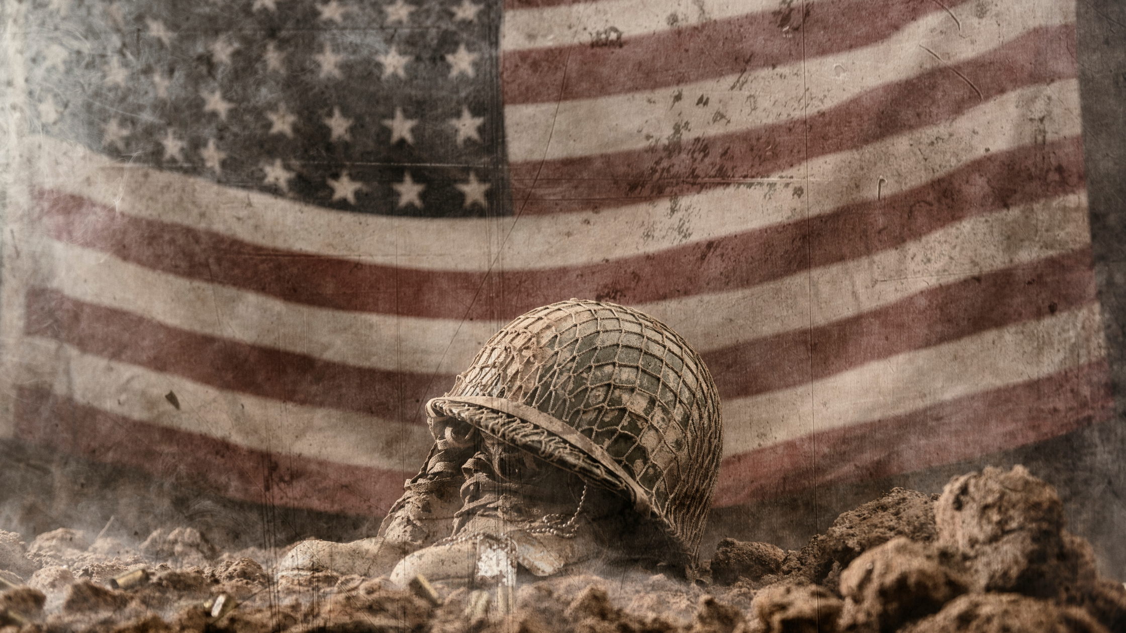 A worn and tattered combat helmet covers a pair of beaten in combat boots, set among rubble. The background is a faded and dusty american flag.