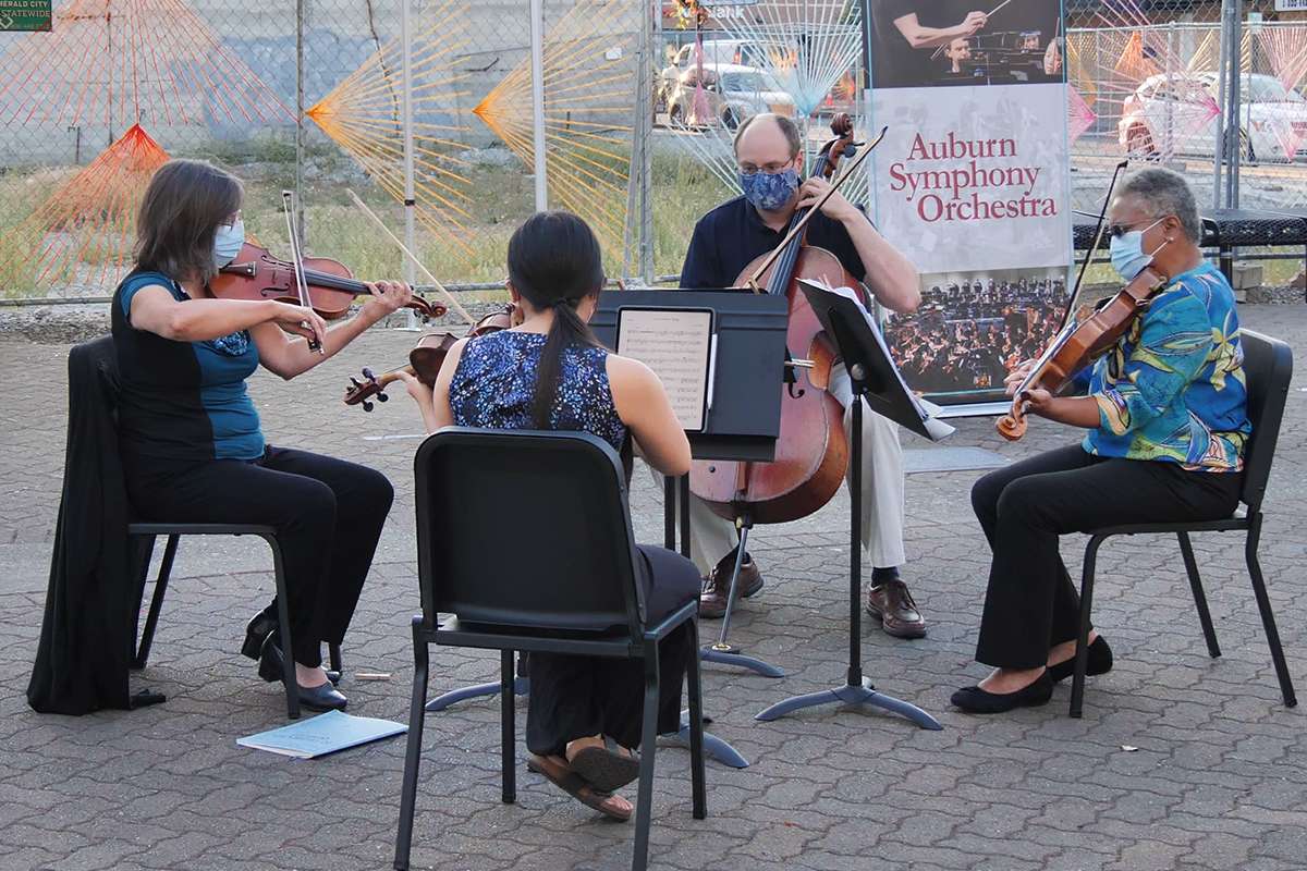 A string quartet plays on a sidewalk