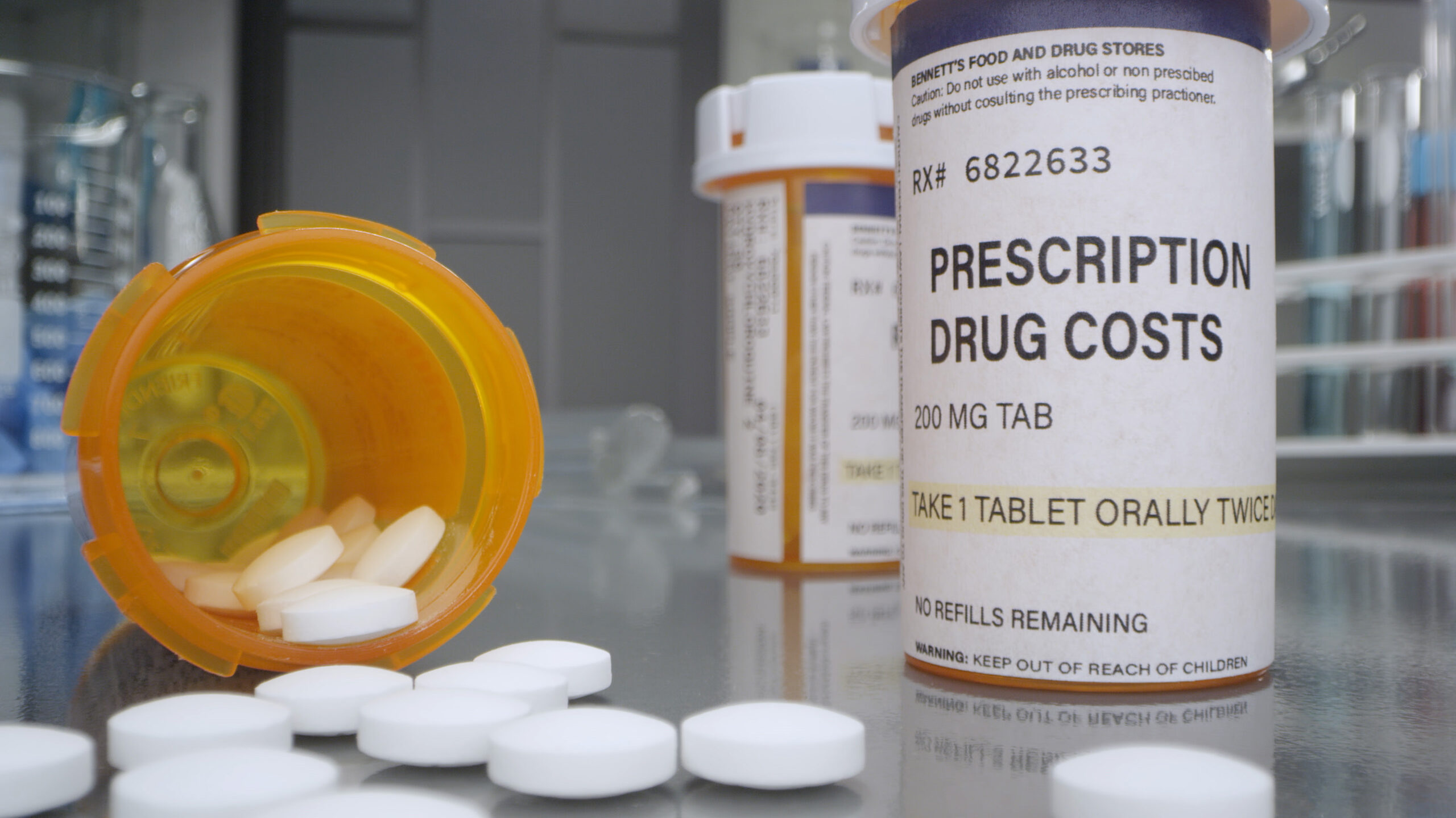 Prescription drug cost bottle with pills out in medical lab