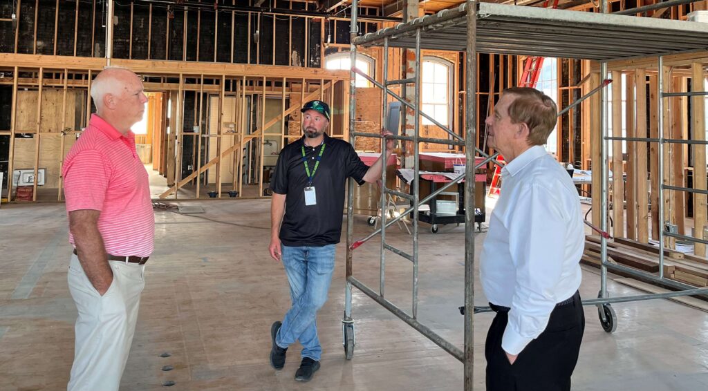 A group of men stand in a construction area, talking about the project.