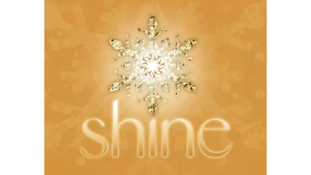 A gold toned image with "Shine" written under a a shimmering gold snowflake in the center.