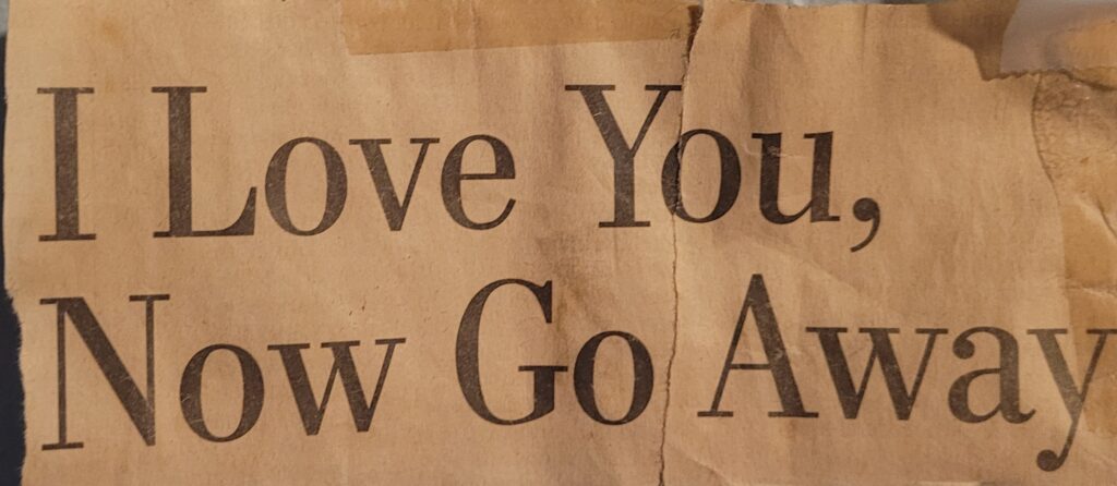 A faded newsprint clipping of a headline that reads "I love you, now go away"